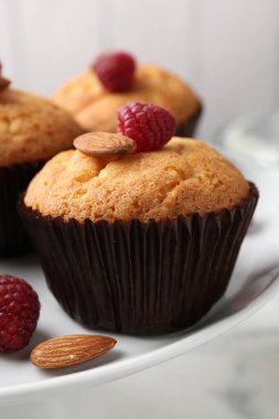 Fresh muffins with raspberries and almonds on table, closeup