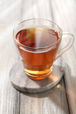 Aromatic black tea in glass cup on wooden table, closeup