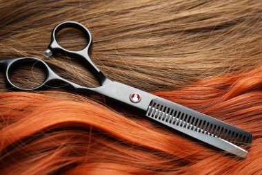 Farklı renklerde güzel saçlar üzerinde makas, yakın plan.