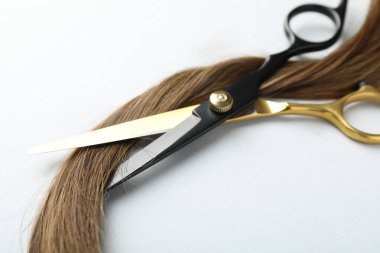 Beyaz arka planda güzel saç teli ve makas, yakın plan.