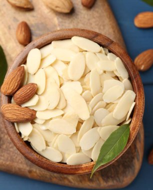 Taze badem taneleri, tüm fındıklar ve yeşil yaprak mavi ahşap masa, üst manzara