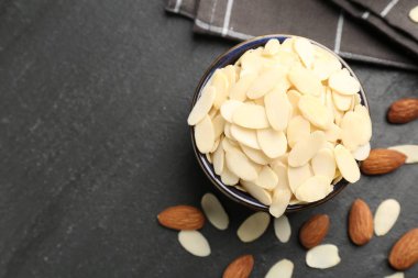 Taze badem gevrekleri kasede ve fındıklar gri masada, düz yerde. Metin için boşluk