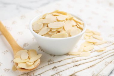 Taze badem taneleri kasede ve kaşıklar beyaz masada, yakın plan.