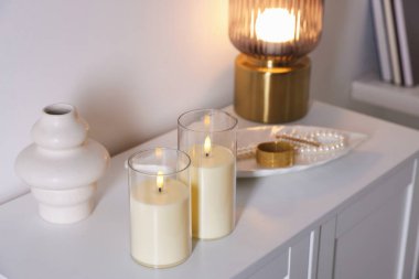 Beyaz dolaptaki dekoratif LED mumlar, vazo, lamba ve mücevherler.