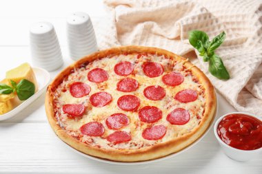 Delicious pepperoni pizza and ingredients on white wooden table, closeup