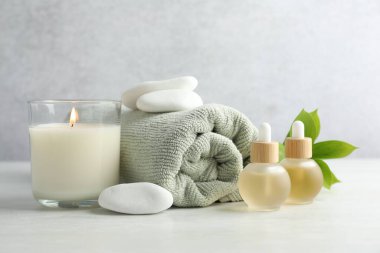 Beyaz masa üzerinde yanan mum ve spa taşlarıyla güzel bir kompozisyon.
