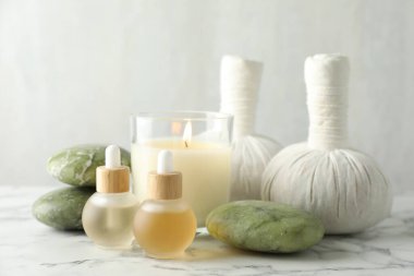 Güzel bir spa kompozisyonu, bitki torbaları ve yanan mumlar beyaz mermer masada, yakın plan.