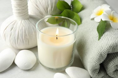 Güzel bir spa kompozisyonu, bitkisel torbalar ve yanan mumlar beyaz masada, yakın plan.