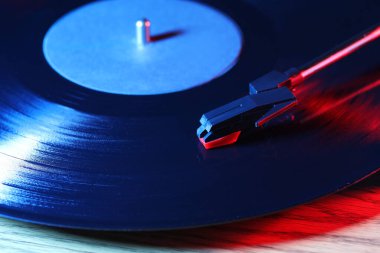Turntable with vinyl record on wooden table, closeup