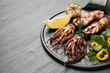 Limon, sarımsak ve siyah masada salata ile servis edilen lezzetli kalamar, yakın plan. Metin için boşluk