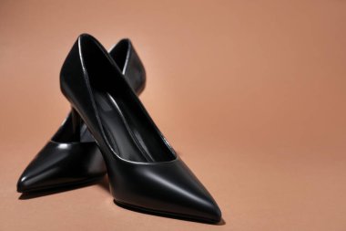 Kahverengi arka planda şık topuklu ayakkabılar, yakın plan. Metin için boşluk