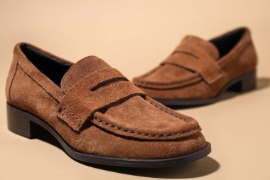 Pair of stylish brown shoes on beige background, closeup