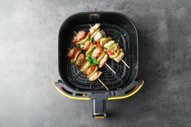 Tavuk ve sebzeli lezzetli şişler gri masada, tavuklu fritöz sepetinde.