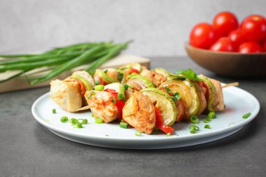 Gri masada tavuk, sebze ve yeşil soğanlı lezzetli şişler.