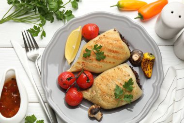 Mantarlı, maydanozlu, domatesli, ahşap masada servis edilen leziz ızgara kalamar parçaları.