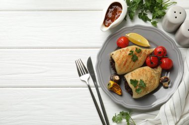 Beyaz ahşap masada servis edilen mantar, maydanoz ve sebzelerle doldurulmuş lezzetli ızgara kalamar parçaları. Metin için boşluk