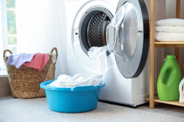 Banyoda çamaşır makinesinin yanındaki plastik leğen.