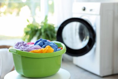 Plastic basin with laundry on white table in bathroom, closeup. Space for text