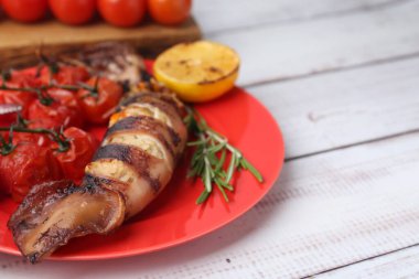 Tasty stuffed squid, rosemary, lemon and tomatoes on light wooden table, closeup. Space for text