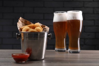 Ahşap masada servis edilen soslu ve biralı kızarmış kalamar halkaları.