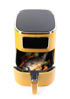 Kızartma makinesinde pişmiş balık, limon ve sebzeler.