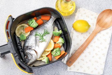 Çiğ balık, limon ve sebzeler kızartma makinesinde açık gri masada, düz yatıyordu.