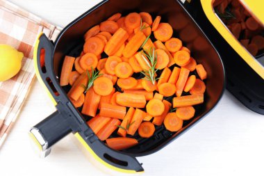 Havuç ve biberiye, tavada, beyaz ahşap masada, üst tarafta.