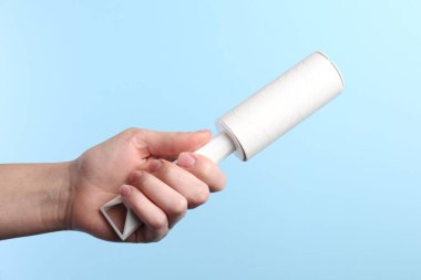 Açık mavi arka planda pamuklu silindirli kadın, yakın plan.