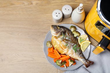 Pişmiş balık, biberiye, limon, sebzeler ve ahşap masada tava, düz yatak. Metin için boşluk
