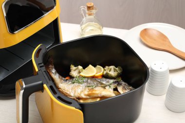 Pişmiş balık, limon ve sebzeler, tavada, beyaz ahşap masada, yakın plan.