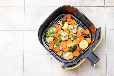 Beyaz fayanslı masada pişmiş havuç, brokoli ve kabak kızartma sepeti, üst manzara. Metin için boşluk