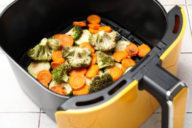 Pişmiş havuç, brokoli ve kabak. Beyaz fayanslı masada tava sepeti, yakın plan.