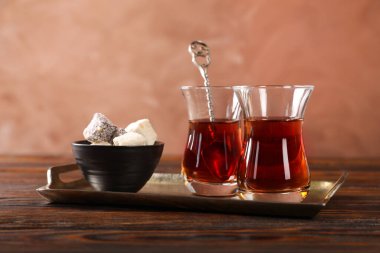 Cam fincanlarda Türk çayı ve ahşap masada tatlı kahverengi arka planda, yakın planda