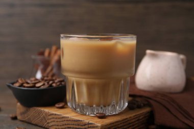 Tasty iced coffee with milk and beans on wooden table, closeup