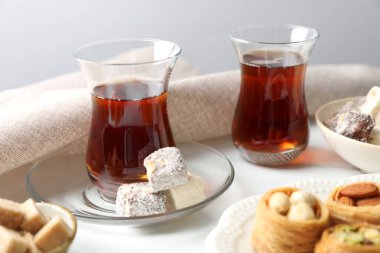 Geleneksel Türk çayı, esmer şeker ve tatlılar beyaz masada, yakın plan