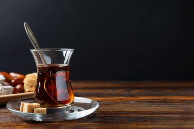 Geleneksel Türk çayı, kahverengi şeker ve ahşap masadaki tatlılar. Metin için boşluk