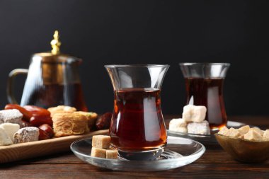 Geleneksel Türk çayı, kahverengi şeker ve tatlılar ahşap masada, yakın plan