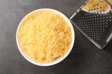 Gri masada rendelenmiş peynir ve rende.