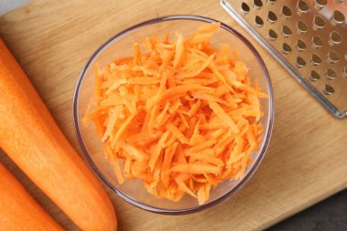 Tam ve rendelenmiş havuç ve rende gri masada, düz yatıyordu.