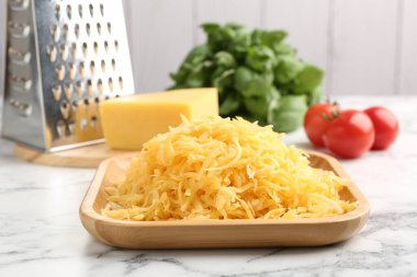 Beyaz mermer masada rendelenmiş peynir, rende ve ürünler, yakın plan.