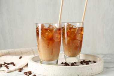 Sütlü buzlu kahve ve beyaz mermer masada fasulye.