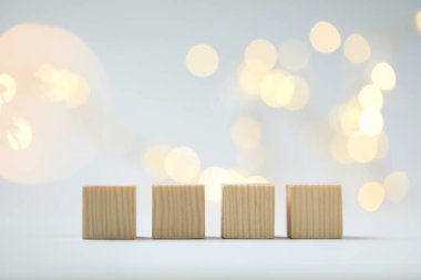 Blank wooden cubes on light background with blurred lights, space for text. Bokeh effect