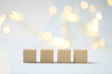 Blank wooden cubes on light background with blurred lights, space for text. Bokeh effect