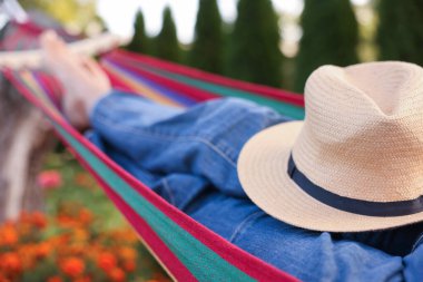 Hamakta dinlenen hasır şapkalı yaşlı kadın, yakın plan.