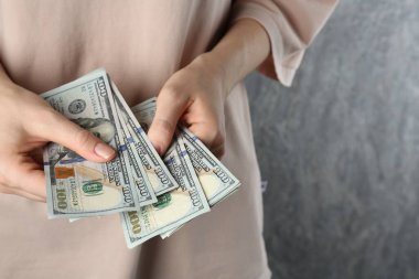 Nafaka. Gri arka planda dolar banknotları olan bir kadın, yakın plan. Metin için boşluk