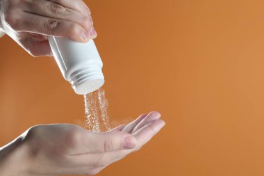 Turuncu arka planda talk pudrası olan kadın, yakın plan. Metin için boşluk