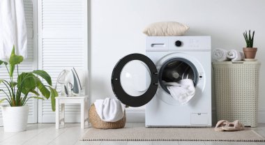 Çamaşır makinesi, sepet ve ev bitkileriyle iç çamaşır odası.