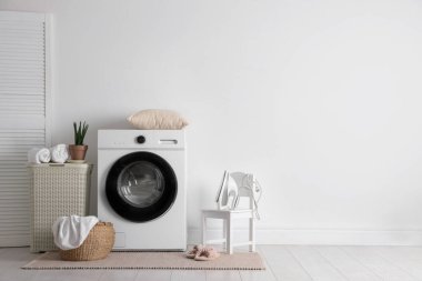Çamaşır makinesi, sepeti ve çiçekli iç çamaşır odası. Metin için boşluk