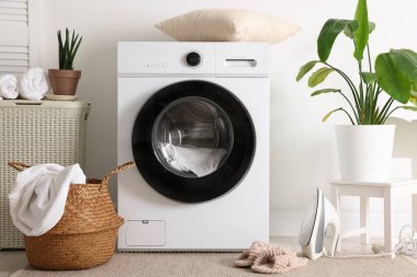 Çamaşır makinesi, sepet ve ev bitkileriyle iç çamaşır odası.