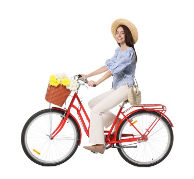 Şapkalı gülümseyen kadın beyaz arka planda bir sepet çiçekle bisiklet sürüyor.